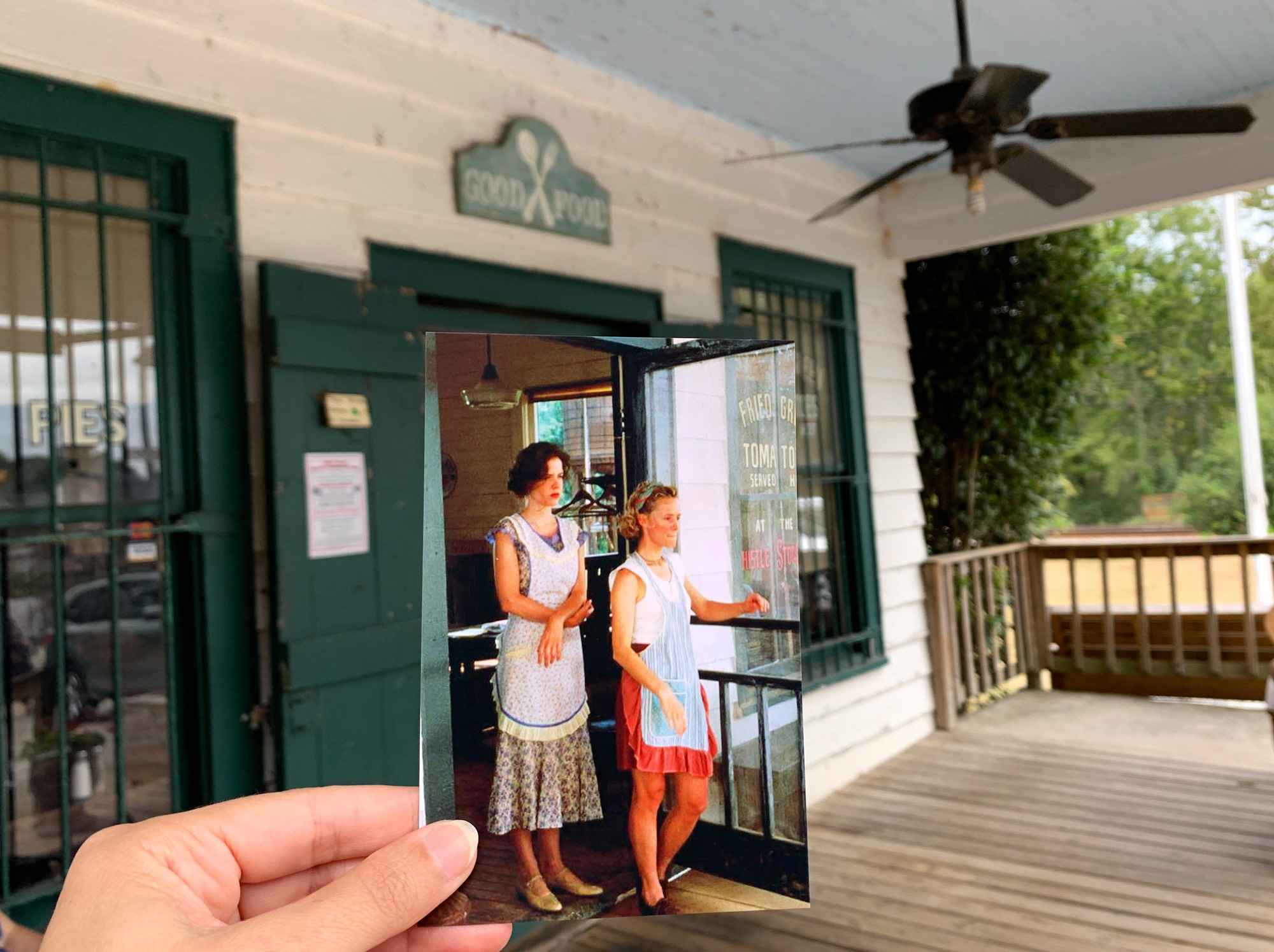 A hand holding a photo from a scene of Fried Green Tomatoes at the Whistle Stop Cafe in Juliette, Georgia