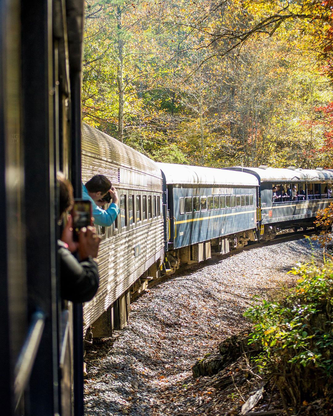 People leaning out of a train to take pictures of the fall scenery in North Georgia