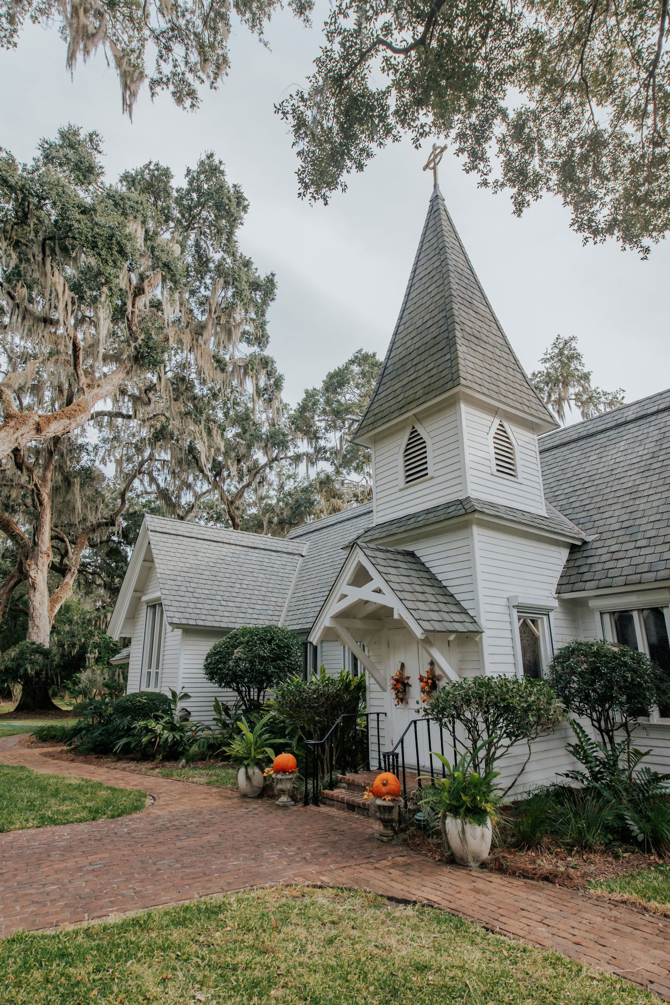 Exterior of Christ Church on St. Simons Island with pumpkins on both sides of the stairs and orange wreaths on the doors
