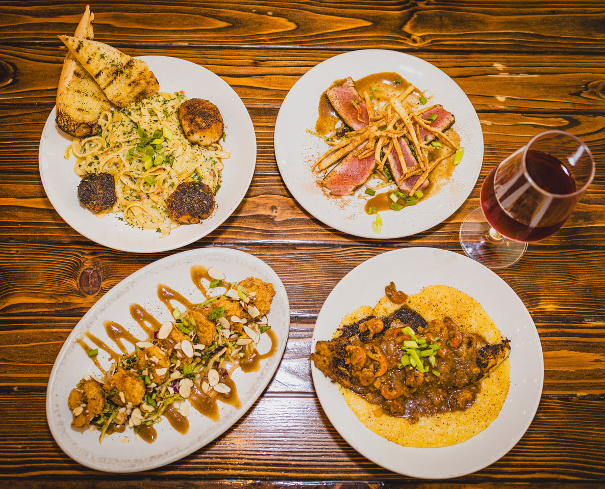overhead view of four plates of food and a drink at Company Supply