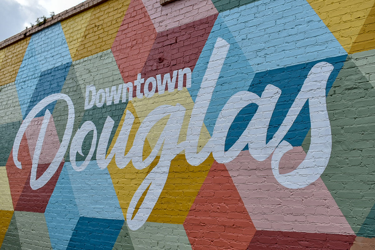 Colorful sign that reads in large white font "Downtown Douglas" in downtown Douglas, Georgia.