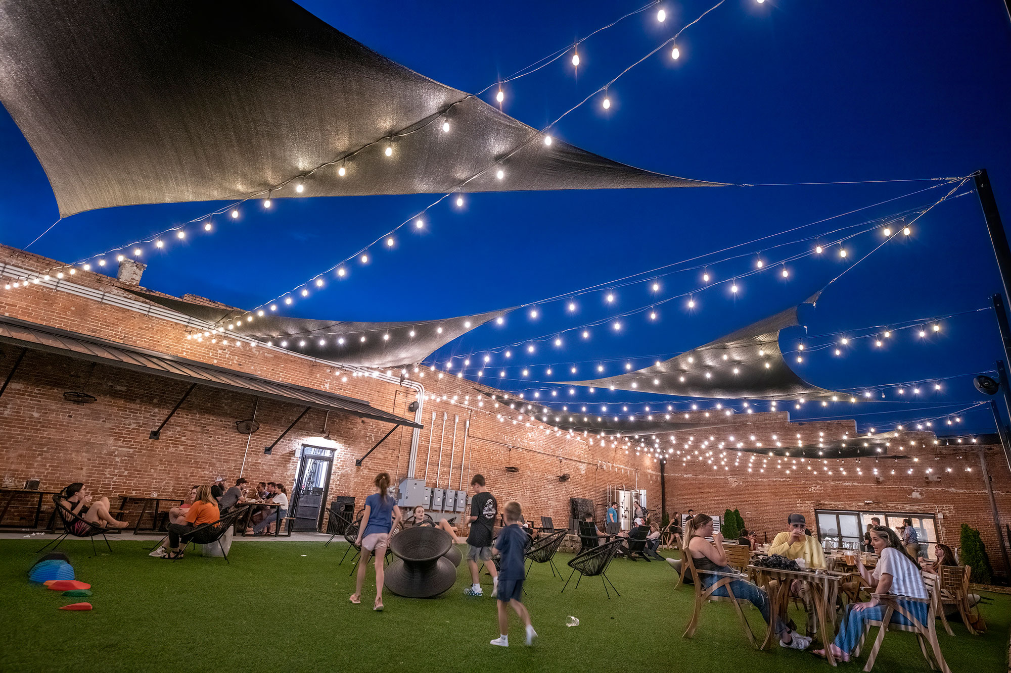 Families enjoying the outdoor courtyard in the evening at Fall Line Brewing Company