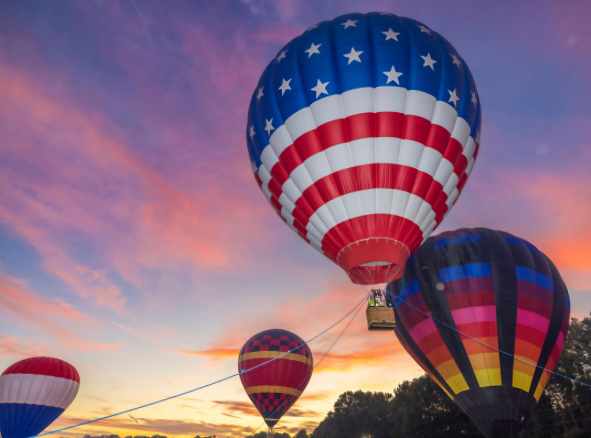 Tethered hot air balloons with a multicolored sunset sky