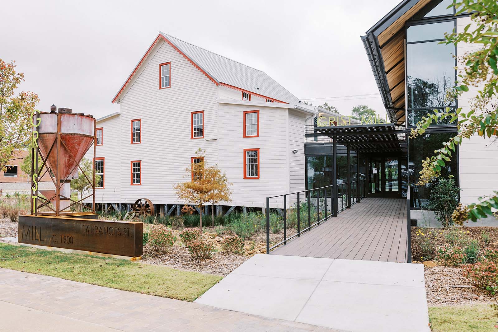 A white house-like building with orange window frames, the outside of The Mill in Georgia.