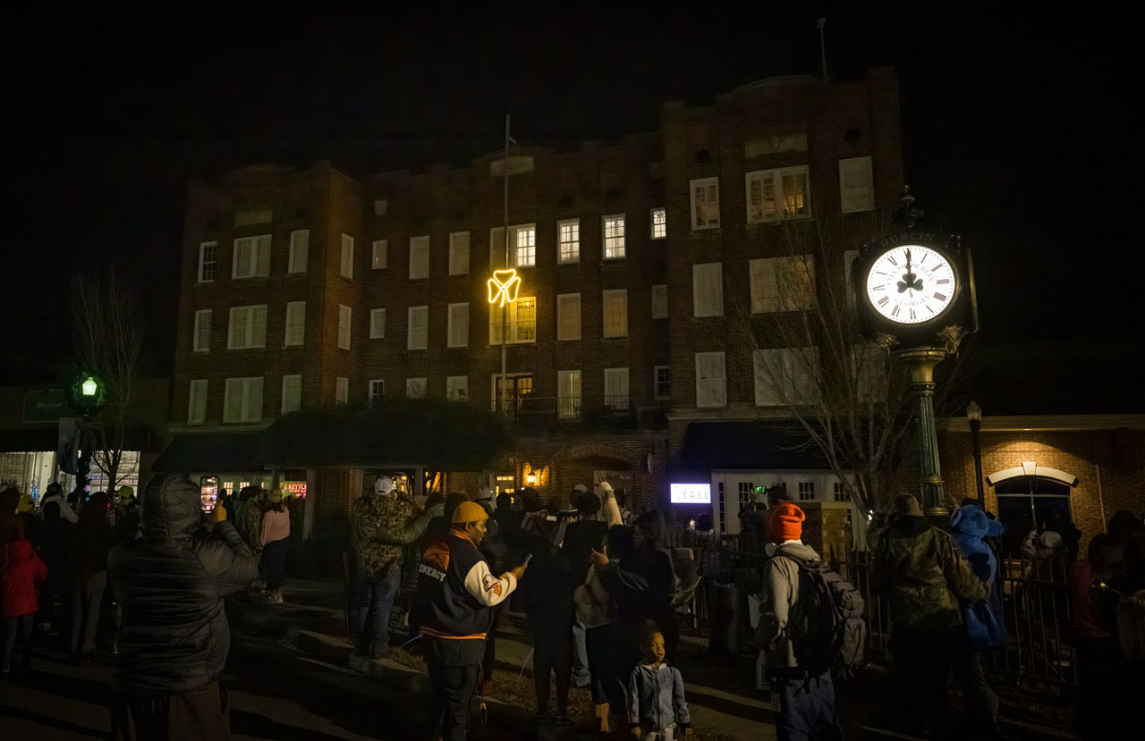 a nighttime crowd watching a neon shamrock on a building in downtown Dublin