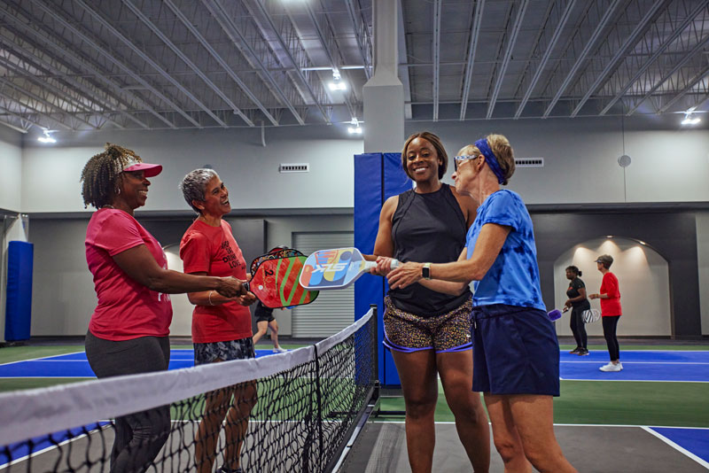 Four women talking between pickleball points at Rhythm and Rally in Macon, Georgia