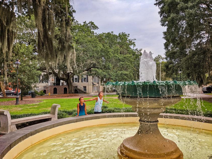 Two kids outside near a fountain at Telfair Square in Savannah, Georgia. Photo by @2traveldads