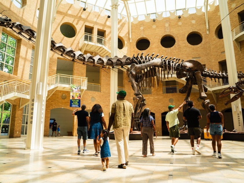 Family in the atrium with dinosaur fossils at Fernbank Museum of Natural History in Atlanta, Georgia