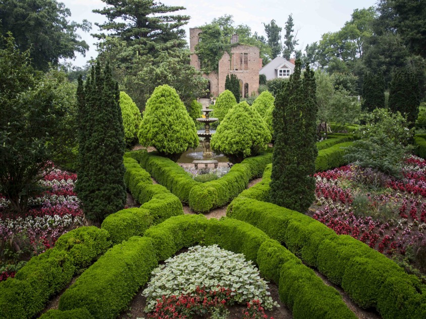 Lush and colorful gardens with a large resort in the background.