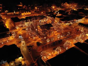 Aerial view of Dahlonega, Georgia, decked out in holiday lights at night. The lights paint the streets in a golden glow.