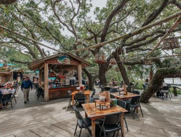 A large outdoor dining deck surrounded by large trees
