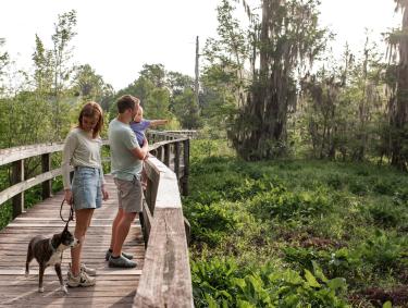 Family and a dog on a boardwalk in Phinizy Swamp Nature Park in Augusta, Georgia