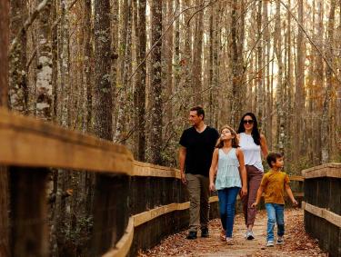 A family walks on the boardwalk at Grand Bay Wildlife Area in Valdosta, Georgia
