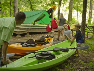 Kids carry a kayak in a campground