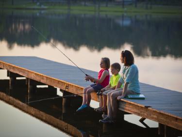 A woman and two children sit on a dock fishing at Seminole State Park in Donalsonville, Georgia