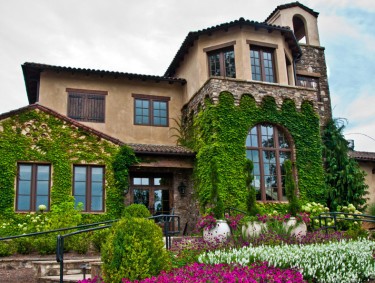 A winery building is surrounded by lush gardens.