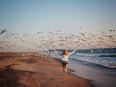 Woman chasing flock of birds on Tybee Island, Georgia. Photo by @brogan_logan