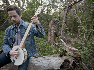 Man playing banjo in the woods