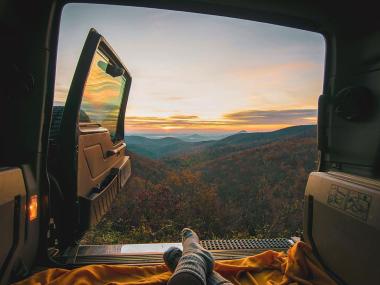 Back door of an SUV opens up to a mountain view of colorful fall foliage.