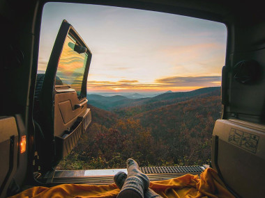 Back door of an SUV opens up to a mountain view of colorful fall foliage.