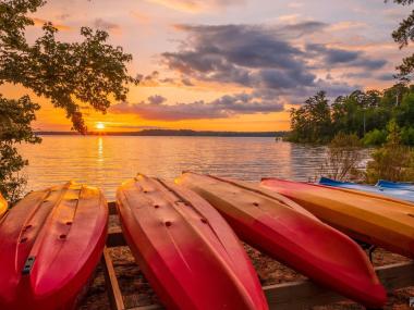 Canoes lined up on the lake with a sunset on the horizon
