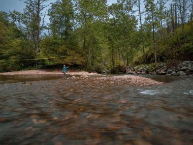 person fishing on a rushing river