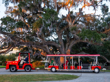 Passengers riding a tram decorated with holiday lights