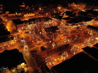 Aerial view of Dahlonega, Georgia, decked out in holiday lights at night. The lights paint the streets in a golden glow.