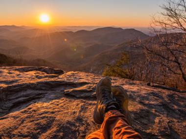 Hiker watching sunset on Preacher's Rock in Cleveland, Georgia. Photo by @afearfuljourney