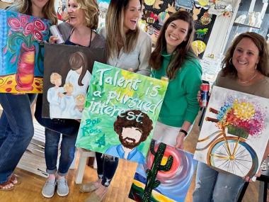 Group of women holding paintings