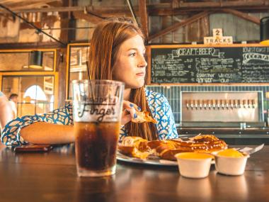 woman eating a pretzel and with a beer at Crooked Finger Brewing in Dublin, Georgia