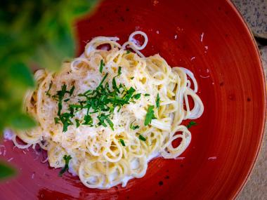 A red plate with pasta and cream sauce at Trattoria di Napoli in Perry, Georgia