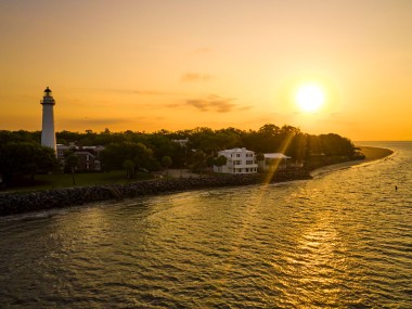 View of St. Simons Island Lighthouse from the water with the rising sun
