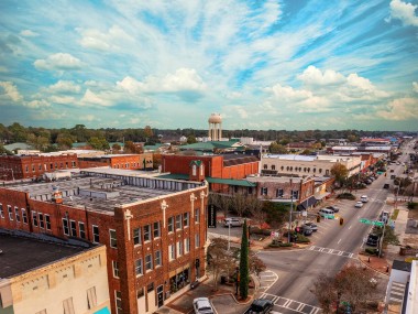 Aerial view of Douglas, Georgia, with a sunny blue sky above and buildings below.