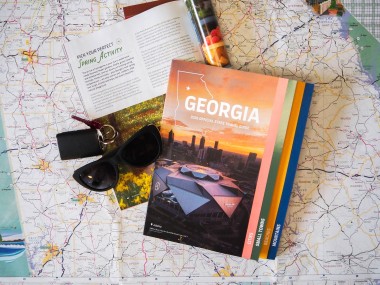 2026 Georgia Travel Guide with sunglasses and keys on a map background