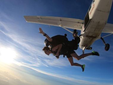 Tandem skydivers float through the air after jumping from an airplane