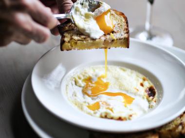 A fried egg on toast dripping into a bowl of grits at Miller Union in Atlanta, Georgia