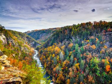 A river flows through a gorge with colorful mountains on both sides.