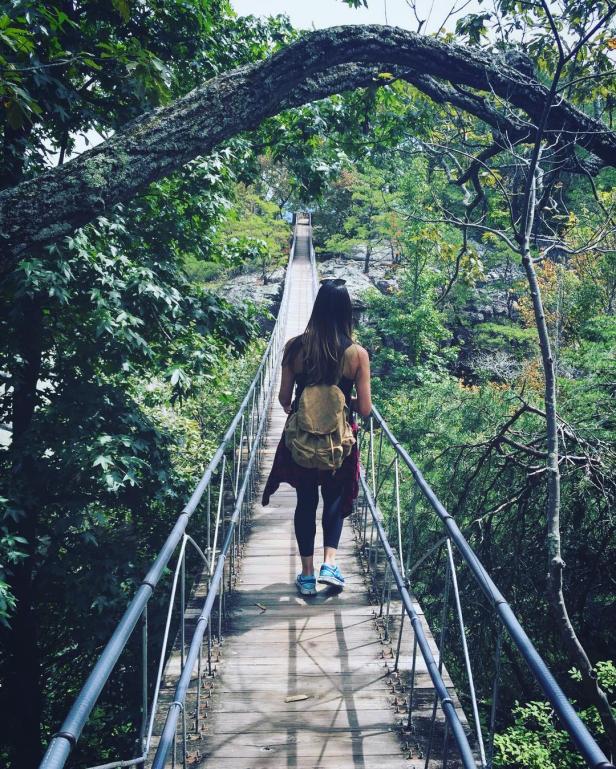 Woman walking on the Rock City Bridge in Lookout Mountain, Georgia. Photo by Helga Fontanez, @helgadenisse