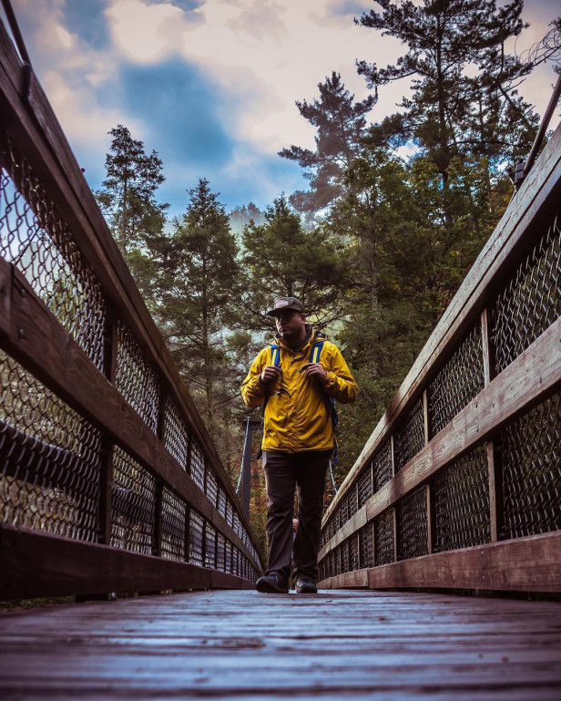 Hiker walking on the Tallulah Gorge bridge in Tallulah Falls, Georgia. Photo by Adrian Thomas, @thegreatkingace