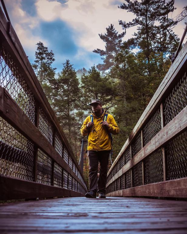 Hiker walking on the Tallulah Gorge bridge in Tallulah Falls, Georgia. Photo by Adrian Thomas, @thegreatkingace