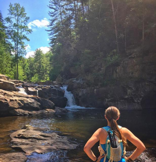A woman looking at a waterfall in a rocky canyon.