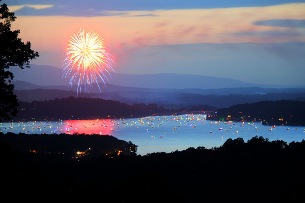 Fireworks fill the sky over a large lake