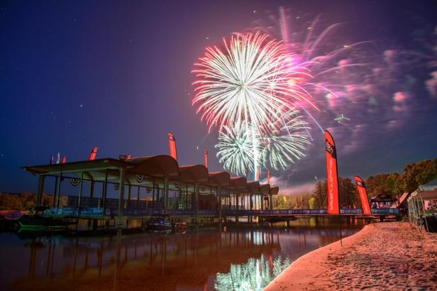 Colorful fireworks fill a dark sky over the water