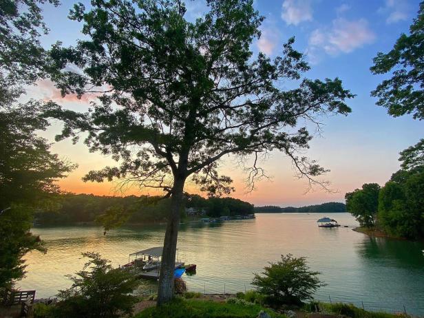 The sun sets behind Lake Nottely with trees in the foreground.