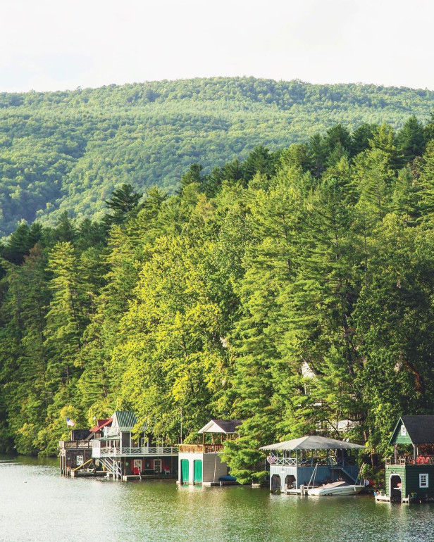 Homes sit along a lakefront surrounded by mountains.