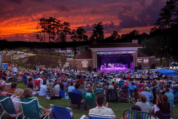 People watching a concert at Sweetland Amphitheatre in LaGrange, Georgia with deep orange sunset in the background