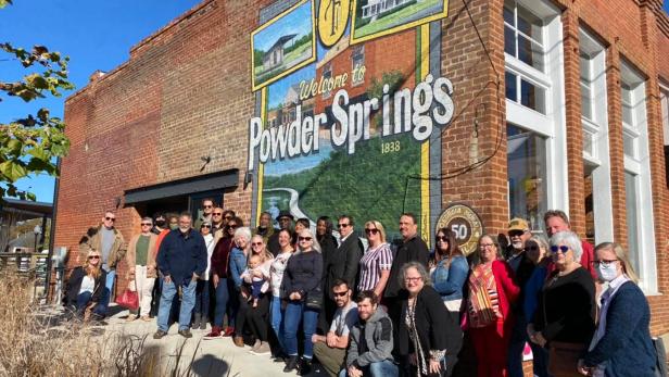 Large group of people standing in front of the "Welcome to Powder Springs" mural by John W. Christian in Powder Springs, Georgia. Photo by Jon Gargis, City of Powder Springs.