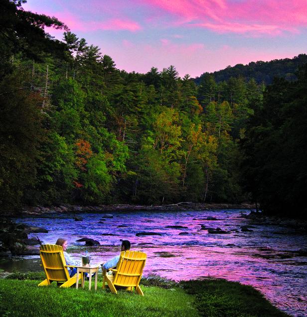 Couple sitting on yellow lawn chairs by the Toccoa River with pink skies in Blue Ridge, Georgia.