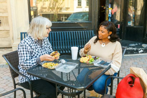 Two ladies sitting at a table outdoors conversing and eating food in Griffin, Georgia.